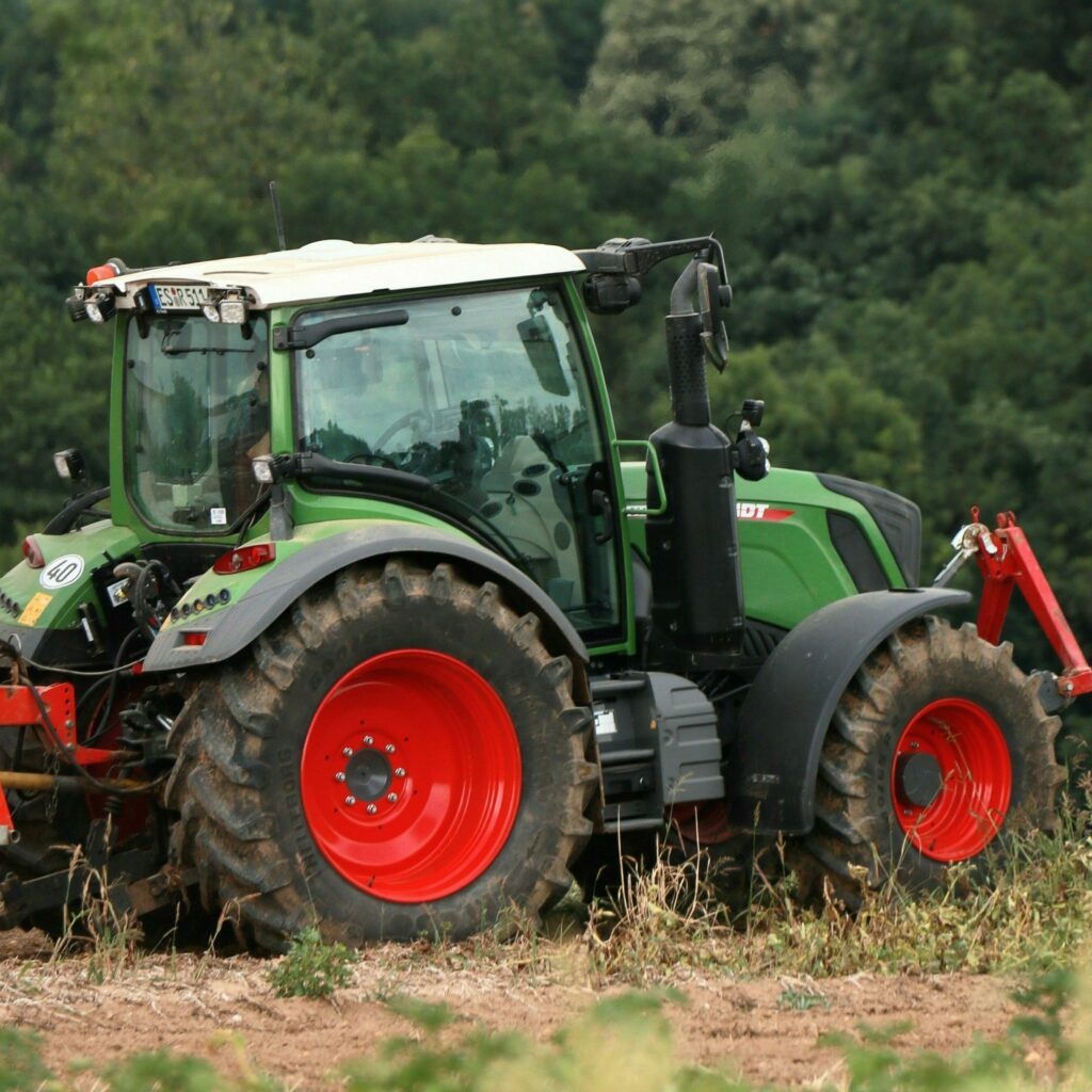 Tractor in a lush field with sunflowers in the foreground, ideal for farming themes.
